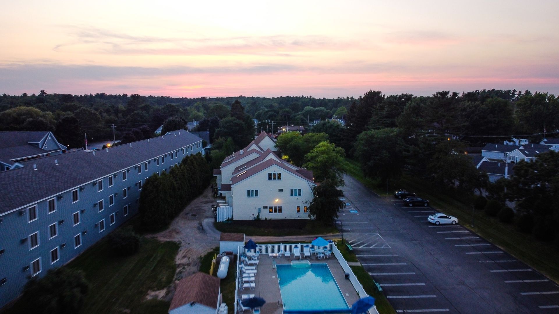 Aerial view of Village by the Sea at dusk, showing the outdoor pool, the buildings and the grounds in Wells, Maine