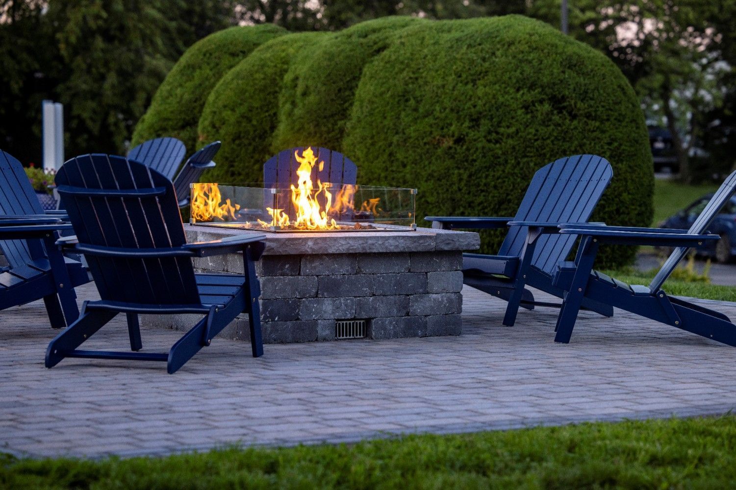 Blue chairs arranged around a lit fire pit on the patio at Village by the Sea