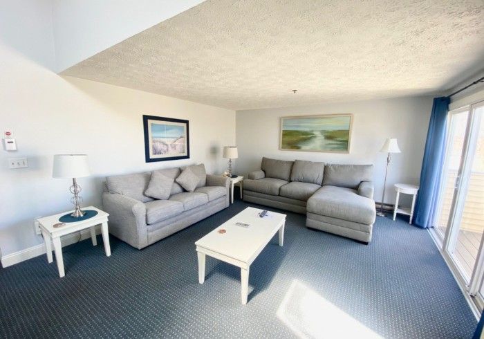 A spacious two-bedroom suite living room with grey couches and natural light at Village by the Sea, Wells, Maine