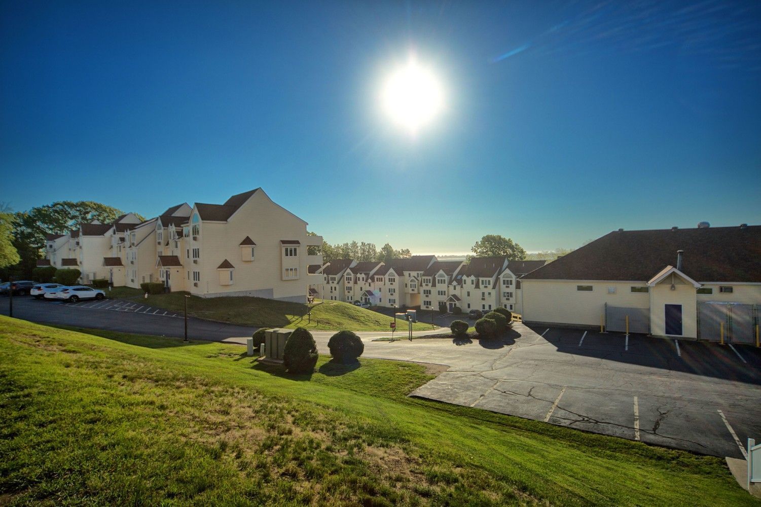 White buildings on a grassy rise at Village by the Sea under a clear blue sky
