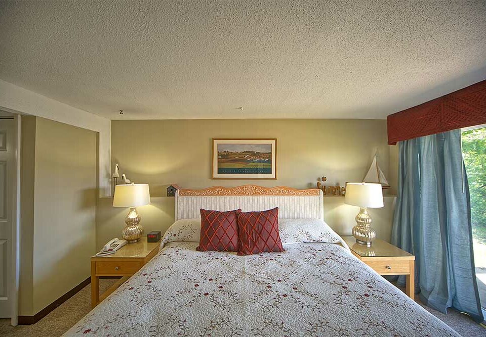 Bedroom with white bedspread and red pillows - wells maine all condominium hotel
