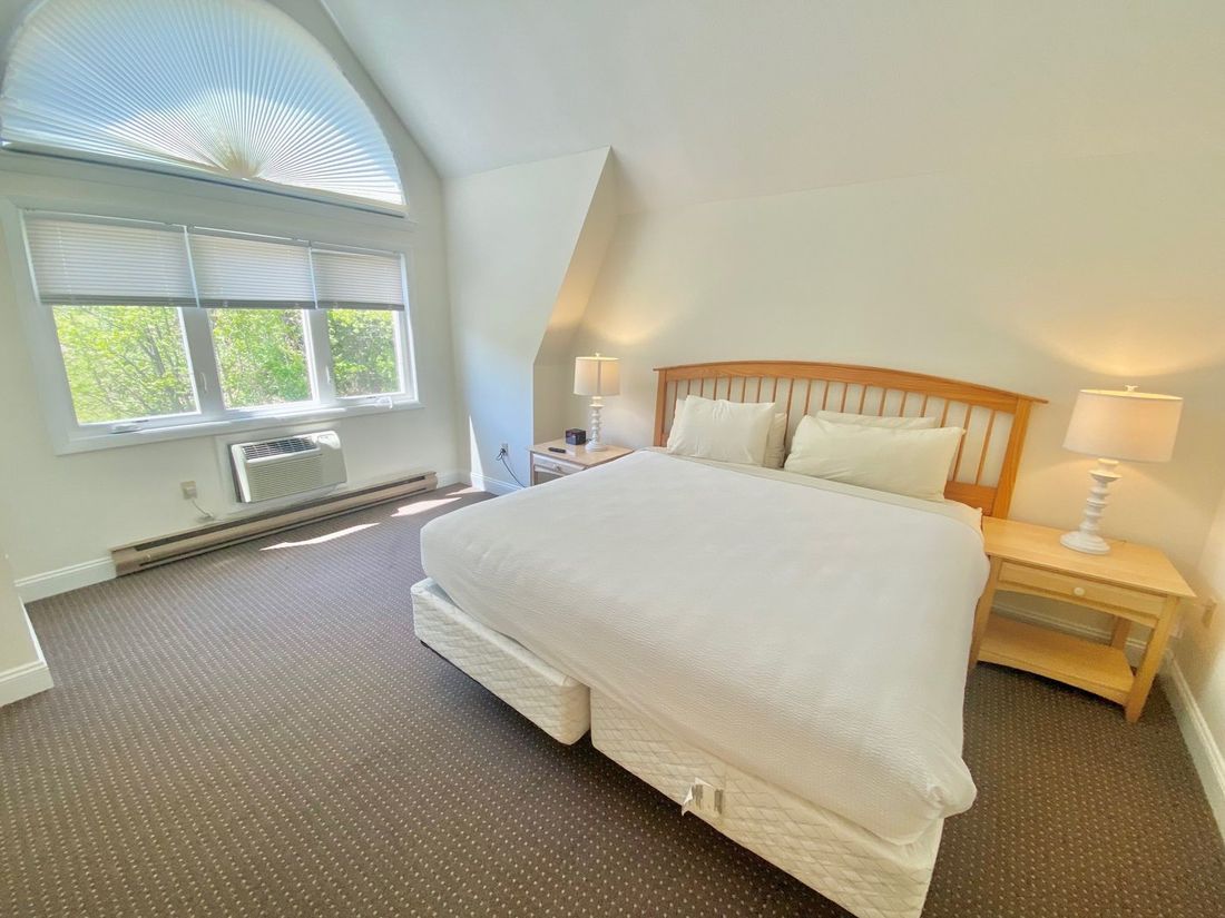 A wide view of a guest room with a large bed, two nightstands, and a window.